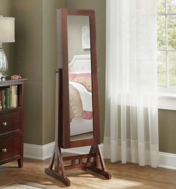 A full length mirror on a wood stand with a door that opens to access a jewelry armoire.