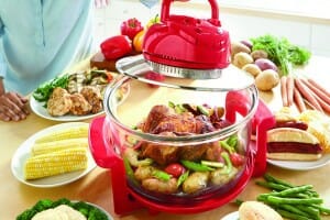 A Ginny's brand air fryer with Roast Chicken and mixed vegetables inside, surrounded by a variety of other foods.