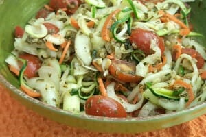 A green bowl filled with a colorful Zucchini Turnip Spiral Salad.