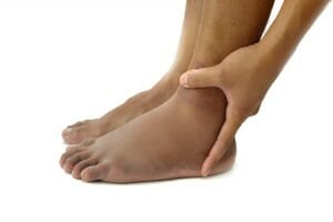 The lower portion of a barefoot African-American person holding one of the ankles.