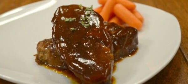 A white plate with a serving of Country BBQ Ribs and baby carrots.