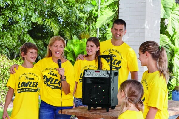 A man, woman, and four children in yellow Family Reunion T-shirts, outside with a karaoke machine.