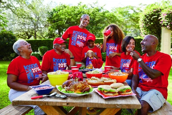 A smiling African-American family in red Family Reunion T-shirts, sitting at a picnic table filled with food.