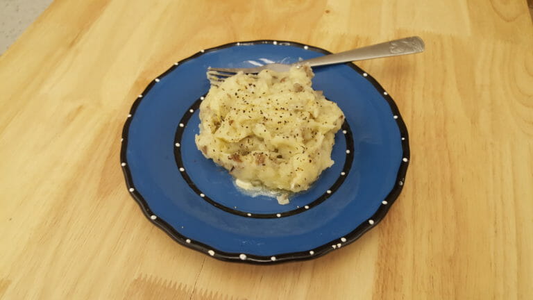 A blue plate with a serving of Lemon Rosemary Mashed Potatoes and a fork.