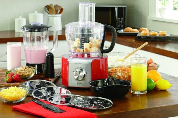 A kitchen counter with Ginny's brand food processor with accessories for blending, juicing, slicing,and shredding.