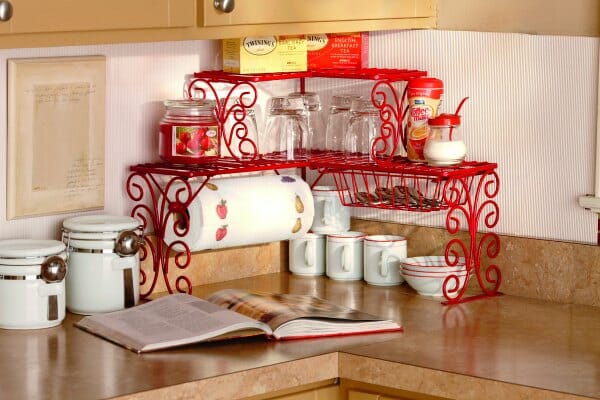 A red scroll, two-tier corner kitchen shelf with paper towel holder and a drawer for kitchen accessories.