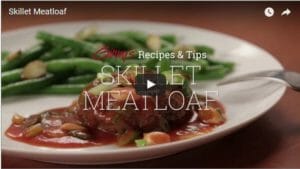A video of Ginny's Recipes & Tips, Skillet Meatloaf - A white plate with sauce-covered meatloaf and green beans.