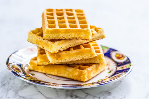 A vintage colorful China plate with a stack of five plain waffles.