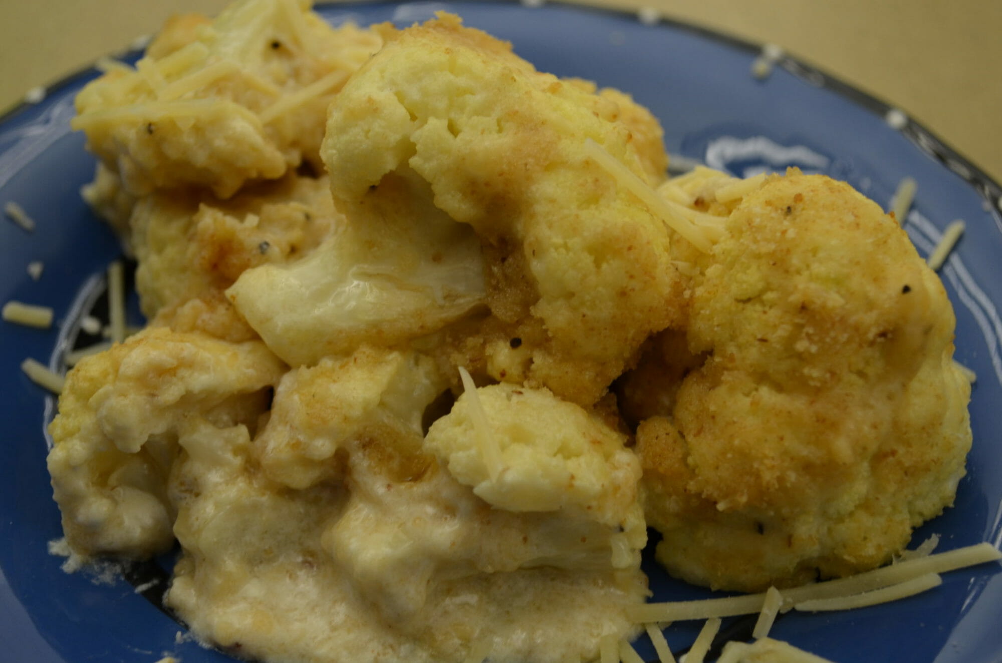 Close-up of a blue bowl filled with Parmesan Cauliflower.