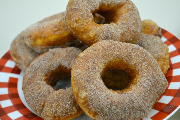 A red and white plate stacked with homemade biscuit donuts dipped in sugar.