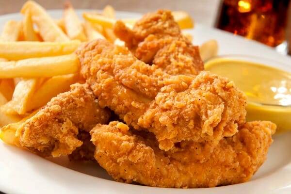 A white plate filled with Classic Fried Chicken and French fries.