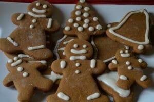 A white and red platter filled with decorated Gingerbread men, bells, and trees.