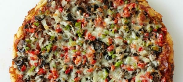 A homemade Kitchen Sink pizza with a multitude of ingredients piled on the crust.