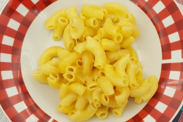 A red and white plate with a serving of golden Microwave Macaroni and Cheese.