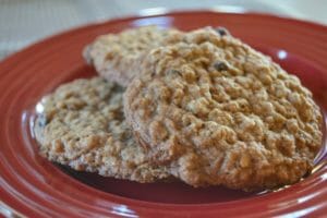 Three Oatmeal Raisin cookies stacked on a red plate.