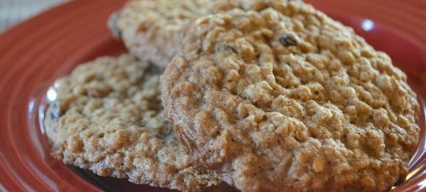 Three Oatmeal Raisin cookies stacked on a red plate.