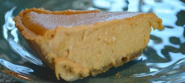 A slice of Pumpkin Cheesecake on a clear plate.