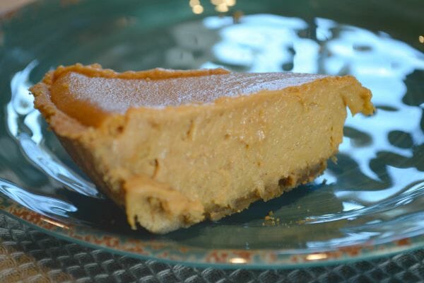 A slice of Pumpkin Cheesecake on a clear plate.