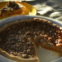 A Pecan Pumpkin Pie in a pie pan, with one slice removed.