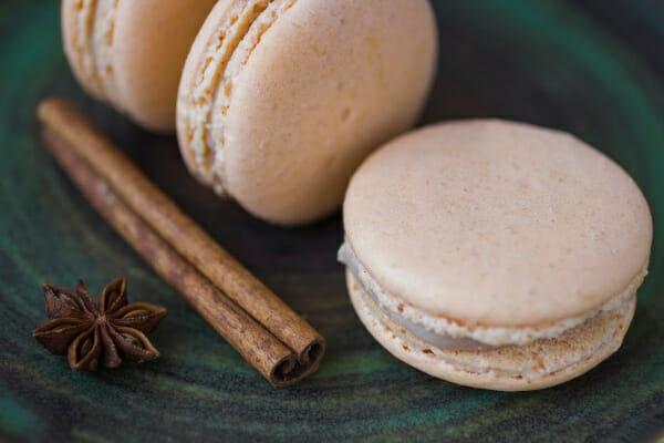 A green plate with three Cinnamon Macarons, a cinnamon stick, and star anise.