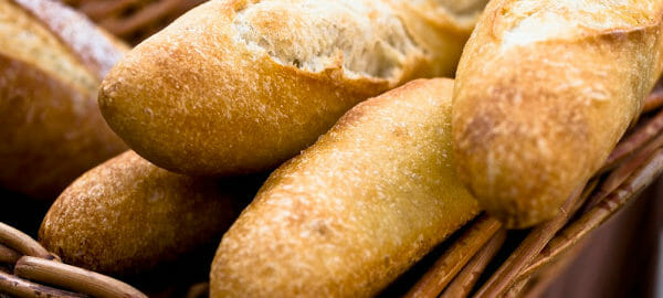 A woven basket filled with five loaves of French Bread.