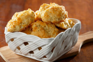 A square white glazed basket filled with golden Garlic Cheese Biscuits.