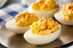 Spicy Dijon Deviled Eggs topped with paprika, placed on a gold platter.