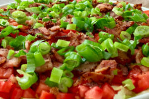 Close-up of a white bowl filled with colorful BLT dip.