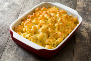 A red and white casserole dish filled with baked Macaroni and Cheese.