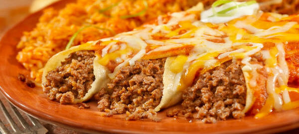 A rust-colored plate filled with beef enchiladas, refried beans, and rice.