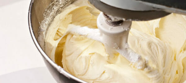 Close-up of cream cheese frosting inside the bowl of a stand mixer.