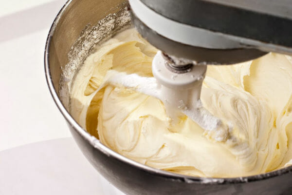 Close-up of cream cheese frosting inside the bowl of a stand mixer.