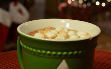 Close-up of a green mug filled with Homemade Hot Cocoa, topped with floating mini marshmallows.