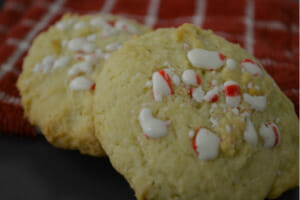 Two sugar cookies on a red check towel, baked with pieces of chopped peppermint candies.