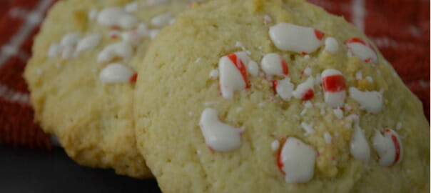 Two sugar cookies on a red check towel, baked with pieces of chopped peppermint candies.